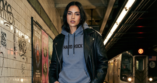 A woman wearing the Hard Rock Comfy hoodie at a subway platform. 